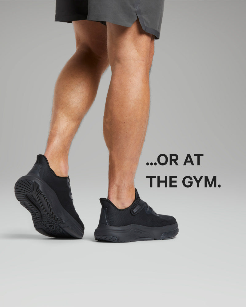 Person wearing black athletic shoes on a gray background with text '...OR AT THE GYM.'