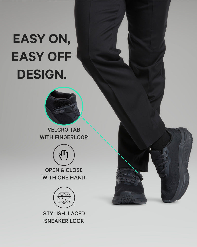 Person wearing black pants with a velcro tab and fingerloop design, on a gray background.