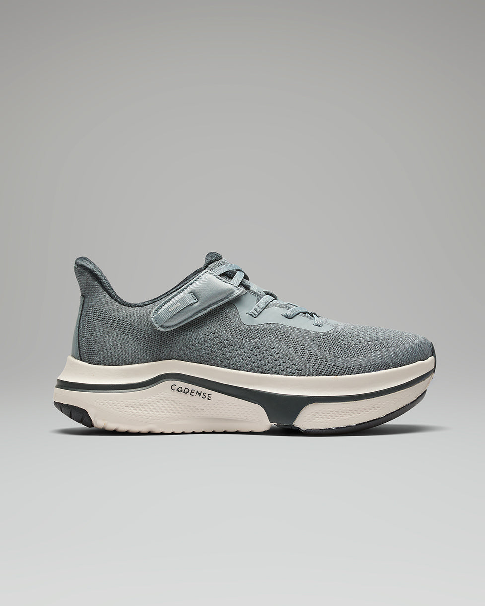 Gray athletic shoe with white sole on a gray background