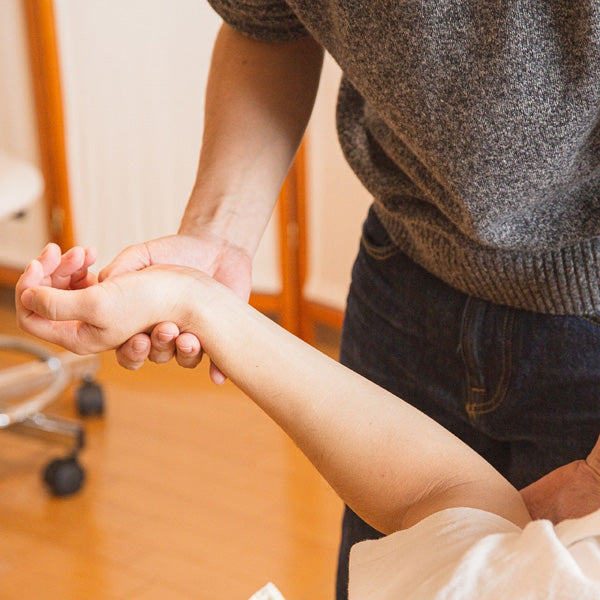 Person holding another person's hand in a close-up shot, with a blurred indoor background.