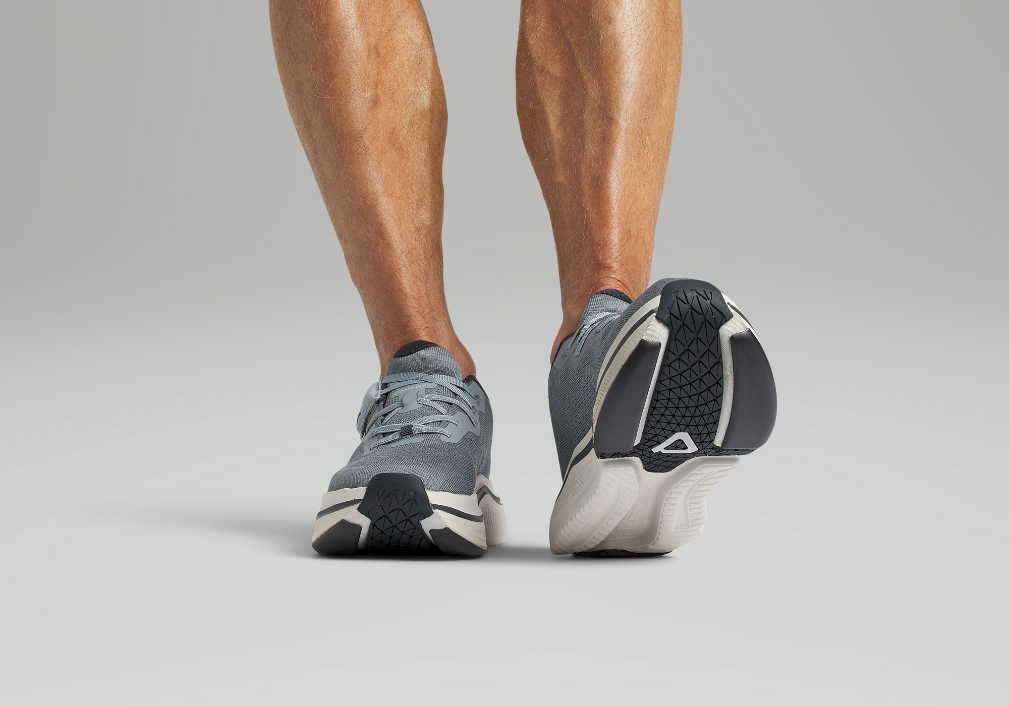 Gray athletic shoes worn by a person on a plain background