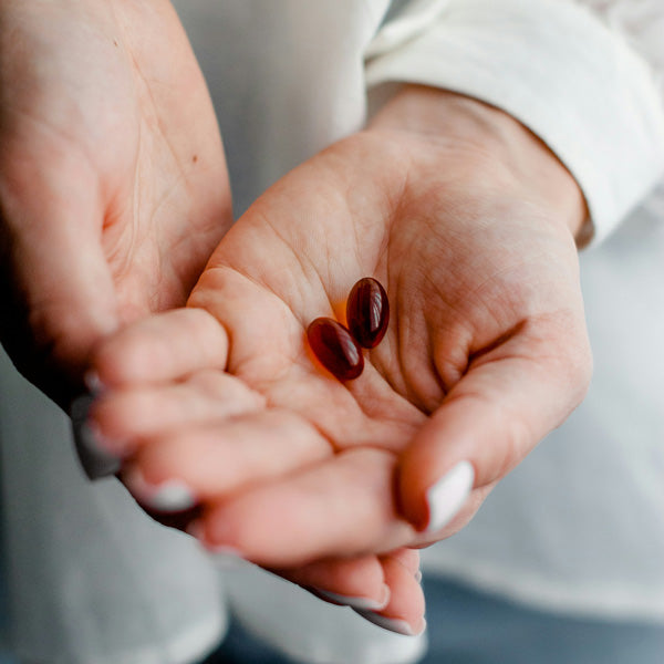Two red pills held in a person's open palms.