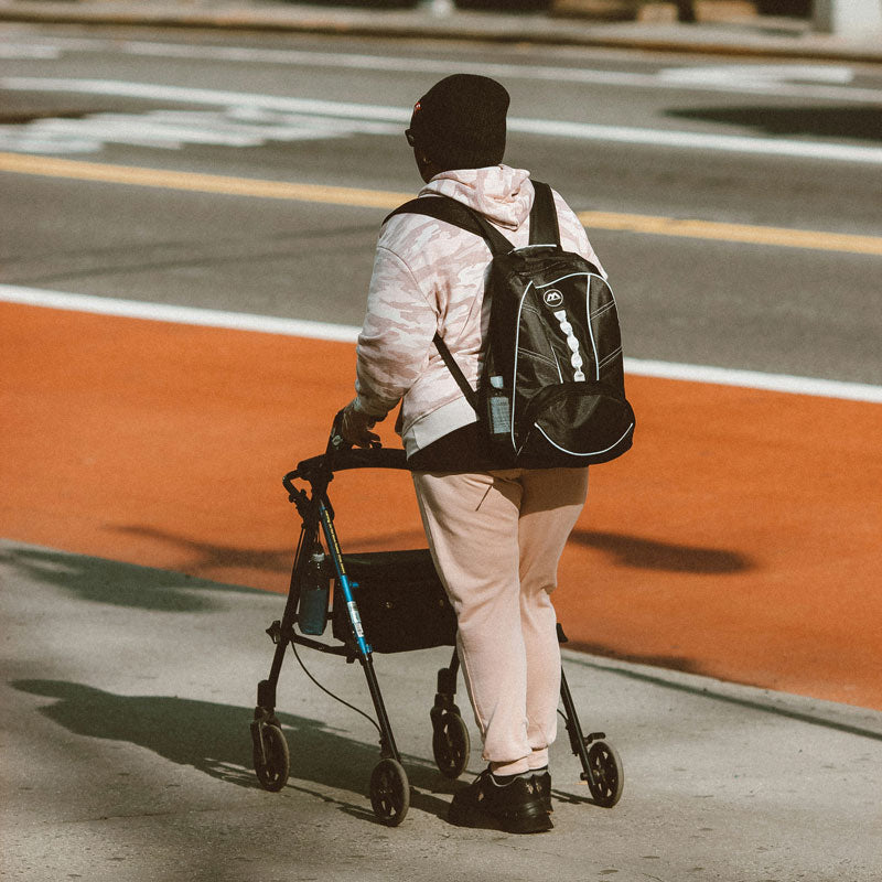 Person with a walker and backpack walking on a street