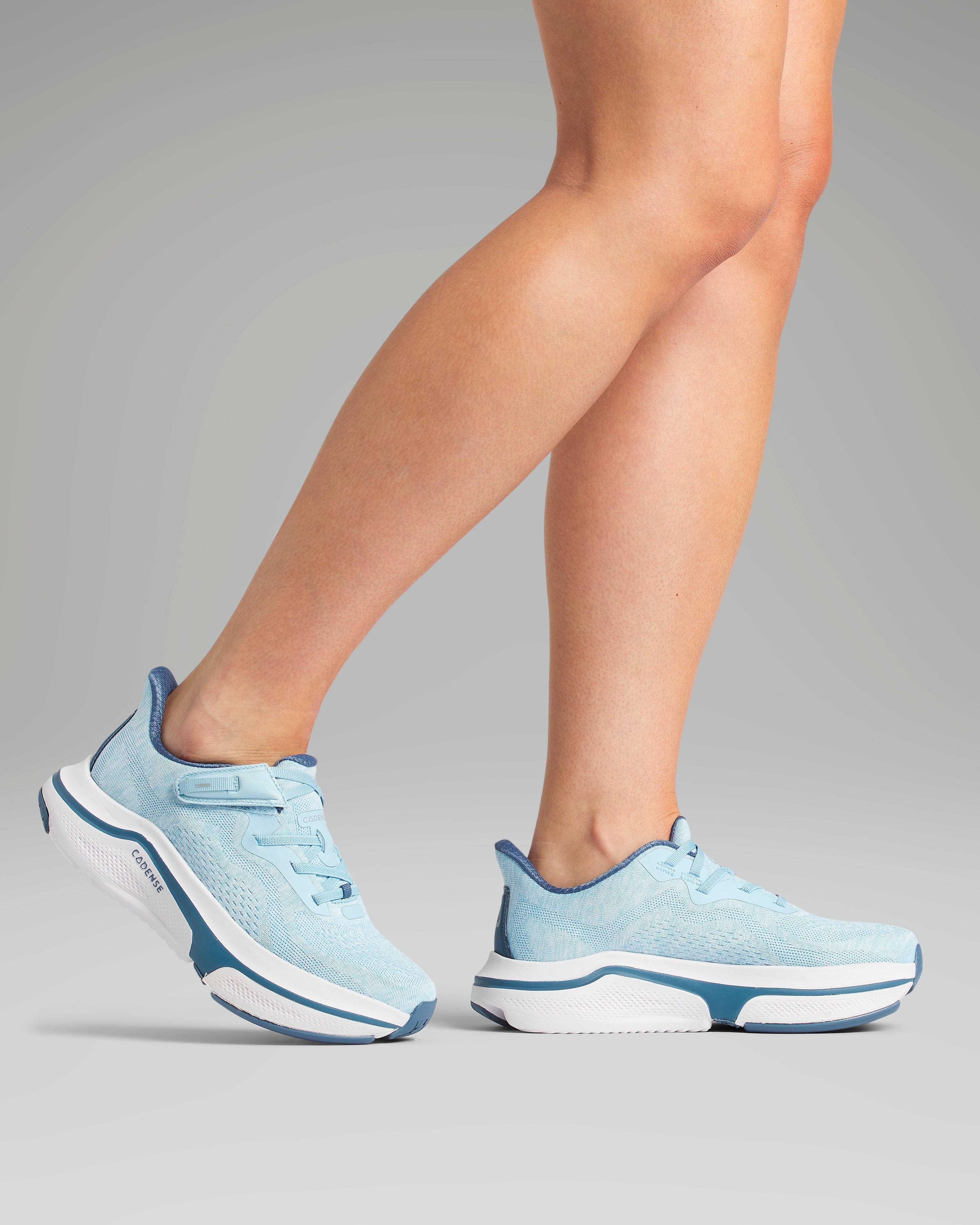 Light blue athletic shoes worn by a person on a gray background