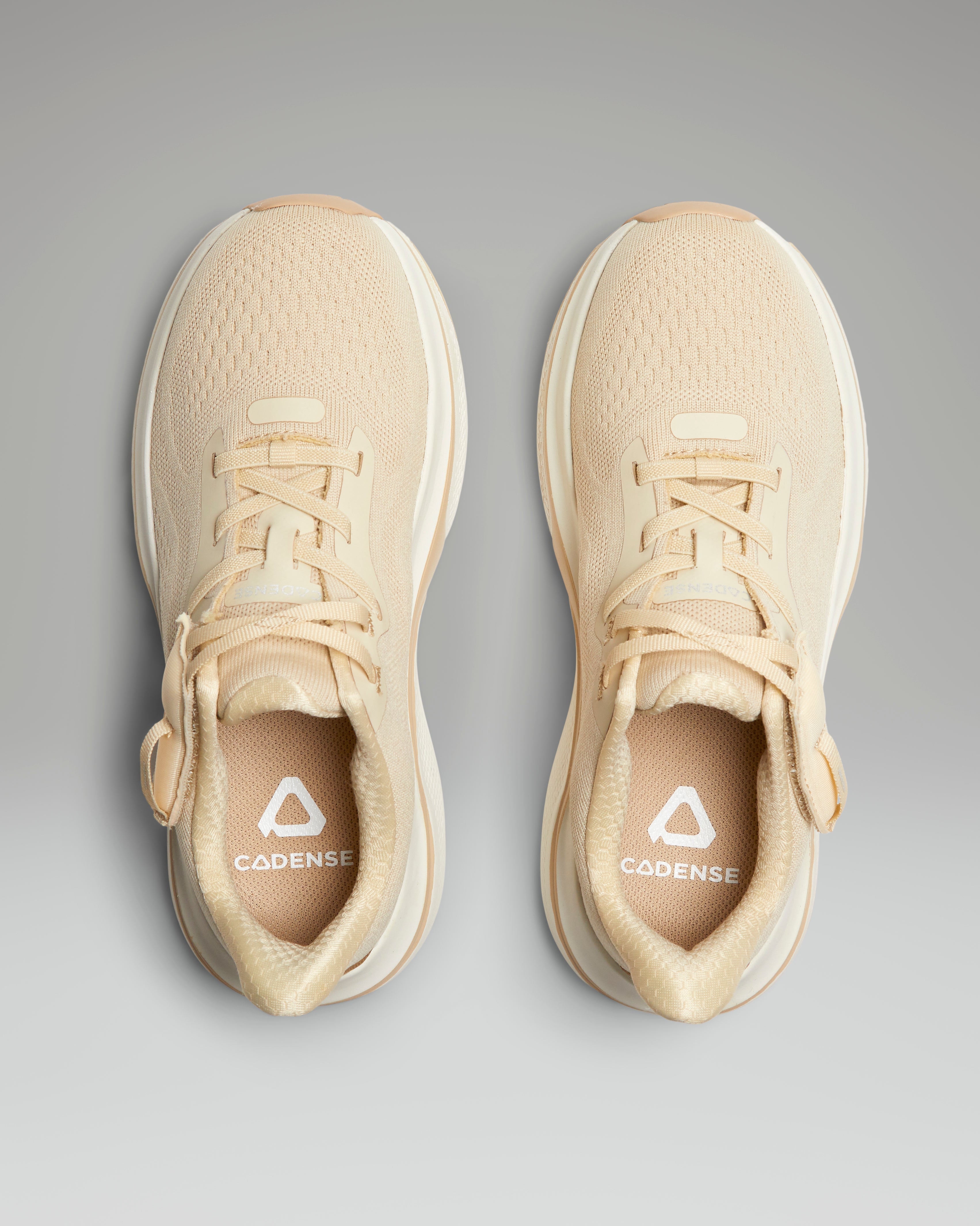 Beige running shoes with a visible brand logo on a gray background