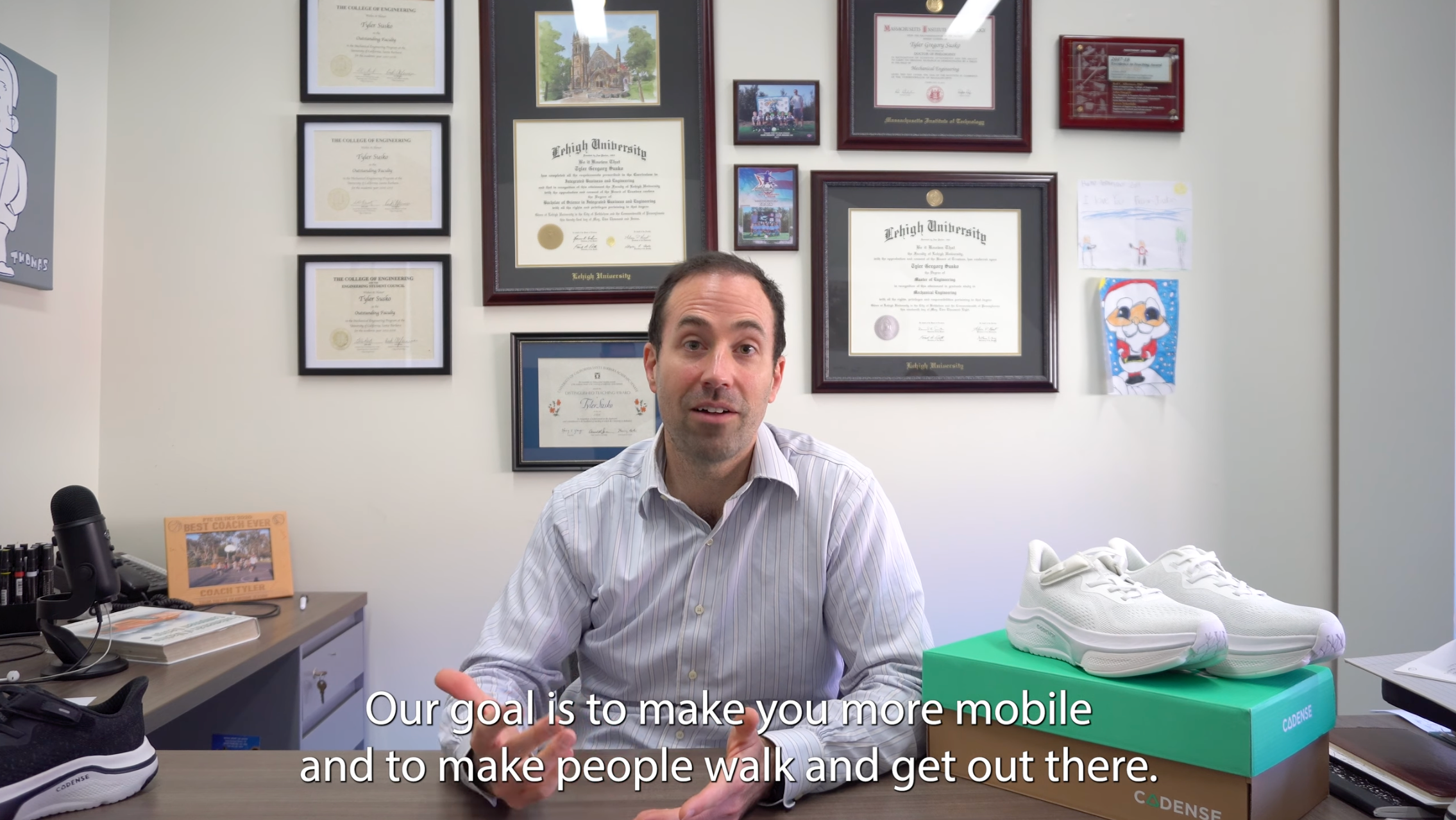 Man sitting at a desk with shoes and certificates on the wall